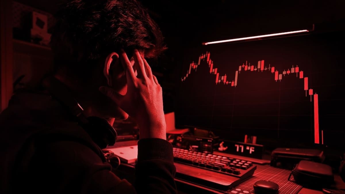 Waarom de cryptomarkt felrood het weekend begint Een afbeelding met een rood filter waarbij een cryptohandelaar gefrustreerd en gestresst naar een hard gecrashte crypto koers kijkt
