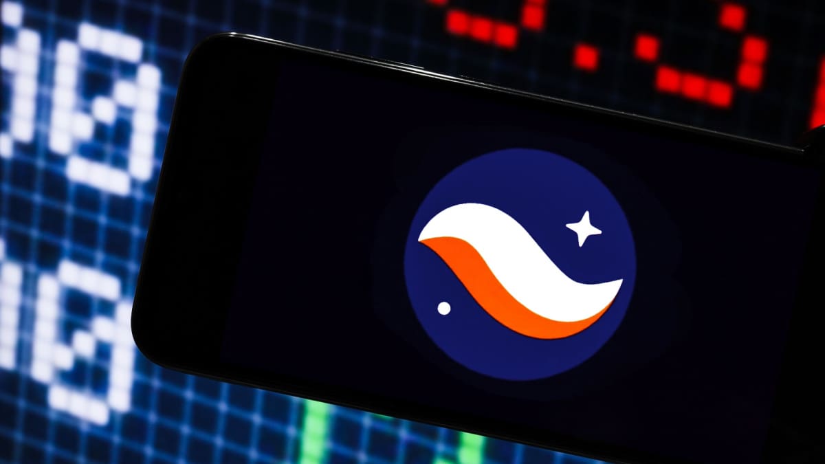 Cryptomunten gericht op privacy stijgen vandaag met tientallen procenten Een afbeelding van het logo van cryptomunt starknet op een mobiele telefoon met op de achtergrond marktdata en grafieken