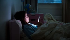 kind-op-bed-met-smartphone 11-jarig meisje verdient €22,3 miljoen maar kiest voor school