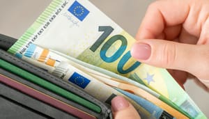 Een foto van een portemonnee met daarin meerdere euro bankbiljetten. Een hand haalt er een briefje van honderd euro uit Een foto van een portemonnee met daarin meerdere euro bankbiljetten. Een hand haalt er een briefje van honderd euro uit