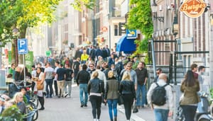 Een afbeelding van Nederlanders en toeristen die lopen door Amsterdam