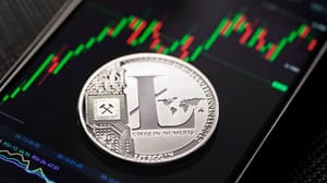 Een afbeelding van een litecoin (LTC) munt op een mobiele telefoon met een grafiek op een crypto exchange Een afbeelding van een litecoin (LTC) munt op een mobiele telefoon met een grafiek op een crypto exchange