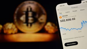 Een afbeelding van een mobiele telefoon met daarop de bitcoin prijs boven de $100.000, met op de achtergrond een BTC munt Een afbeelding van een mobiele telefoon met daarop de bitcoin prijs boven de $100.000, met op de achtergrond een BTC munt