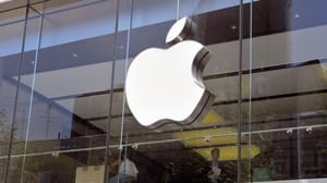 Een afbeelding van het Apple logo op een kantoor, met werkende mensen op de achtergrond