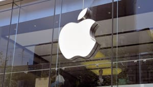 Een afbeelding van het Apple logo op een kantoor, met werkende mensen op de achtergrond Een afbeelding van het Apple logo op een kantoor, met werkende mensen op de achtergrond