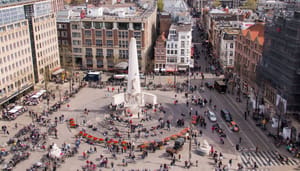Een afbeelding van het plein van de Dam in Amsterdam, met daarbij het monument en een hoop Nederlanders Een afbeelding van het plein van de Dam in Amsterdam, met daarbij het monument en een hoop Nederlanders