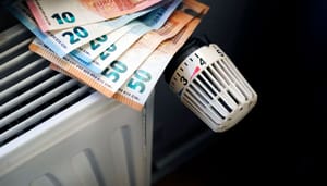 Een afbeelding van eurobiljetten op een verwarming in een huishouden, die vaste lasten moet representeren Een afbeelding van eurobiljetten op een verwarming in een huishouden, die vaste lasten moet representeren