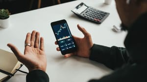 Man trading grafiek telefoon bureau Duizenden Nederlanders verdienen 114% met gratis ‘crypto-supercomputer’