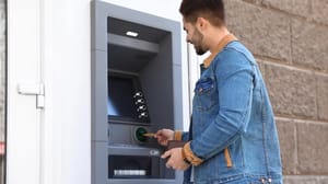 Een afbeelding van een man die aan het pinnen is bij een geldautomaat van een onbekende bank of bedrijf Een afbeelding van een man die aan het pinnen is bij een geldautomaat van een onbekende bank of bedrijf