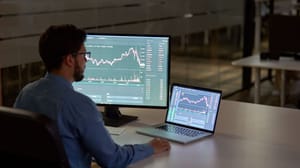 Een afbeelding van een actieve belegger die met twee schermen een bepaalde koers van een aandeel of crypto aan het analyseren is Een afbeelding van een actieve belegger die met twee schermen een bepaalde koers van een aandeel of crypto aan het analyseren is