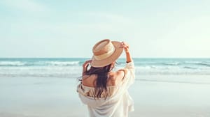 Een afbeelding van een vrouw bij een strand in de zomer die aan het genieten is van haar vakantie