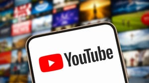 Een afbeelding van het logo van YouTube met op de achtergrond een reeks video's op een scherm