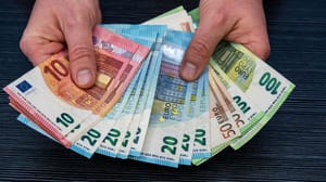 Een afbeelding van twee handen die een reeks bankbiljetten vasthouden