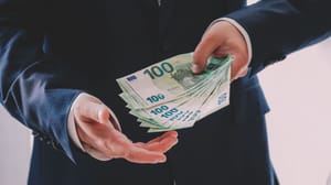 Een afbeelding van een persoon die meerdere honderd euro bankbiljetten vasthoudt Een afbeelding van een persoon die meerdere honderd euro bankbiljetten vasthoudt