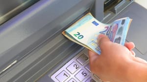 Een afbeelding van iemand die euro bankbiljetten uit een pinautomaat trekt Een afbeelding van iemand die euro bankbiljetten uit een pinautomaat trekt