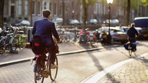 Een elegant geklede man rijdt op een fiets in het centrum van Amsterdam Een elegant geklede man rijdt op een fiets in het centrum van Amsterdam