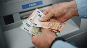 Man neemt eurobiljetten op van pinautomaat Man neemt eurobiljetten op van pinautomaat