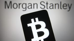 Een afbeelding van bankgigant Morgan Stanley op de achtergrond en op de voorgrond een mobiele telefoon met het bitcoin (BTC) logo Een afbeelding van bankgigant Morgan Stanley op de achtergrond en op de voorgrond een mobiele telefoon met het bitcoin (BTC) logo