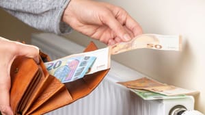 Een afbeelding van een hand die bankbiljetten uit een portemonnee haalt en op een verwarming legt Een afbeelding van een hand die bankbiljetten uit een portemonnee haalt en op een verwarming legt