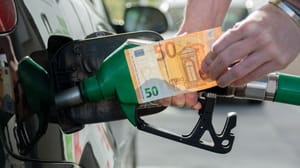 Een afbeelding van een man die aan het tanken is met een vijftig euro briefje in zijn hand Een afbeelding van een man die aan het tanken is met een vijftig euro briefje in zijn hand