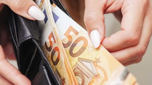 Een afbeelding van vrouwelijke handen die briefjes van 50 euro uit een portemonnee trekken Een afbeelding van vrouwelijke handen die briefjes van 50 euro uit een portemonnee trekken