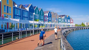 Een afbeelding van twee kinderen die spelen met een step langs het water langs een rij typisch Nederlandse huishoudens Een afbeelding van twee kinderen die spelen met een step langs het water langs een rij typisch Nederlandse huishoudens