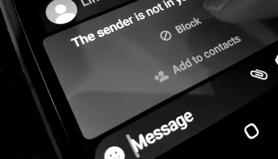 Een zwart wit foto van een SMS afkomstig van een onbekende afzender, die door de ontvanger wordt geblokkeerd