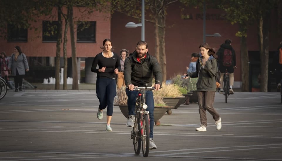 Nederlanders op een plein die fietsen, lopen, hardlopen en zitten