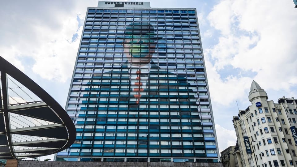 Een afbeelding van 'the son of man' van rene margritte op een gebouw in brussel