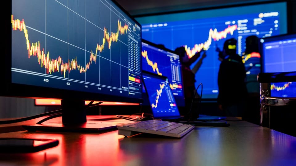 Een afbeelding van een kantoortje van een handelaar in aandelen of crypto's, met veel candle charts op verschillende schermen met data