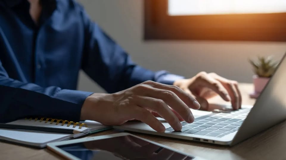 man typt iets op laptop