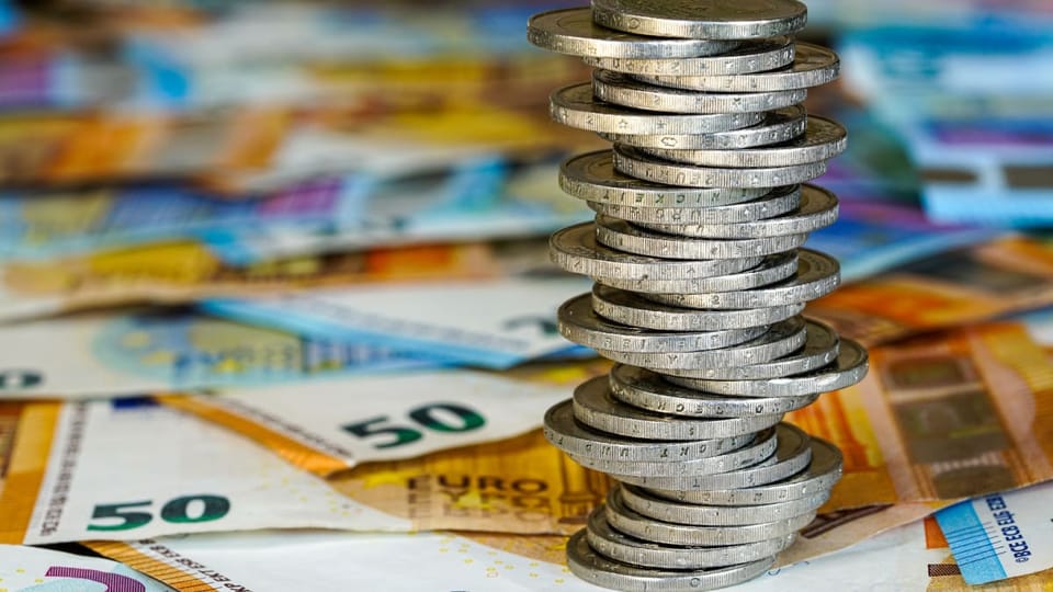 Een afbeelding van een stapel 2 euro munten op briefgeld _ bankbiljetten
