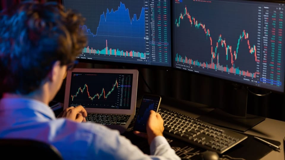 Man bekijkt koersgrafieken achter computer