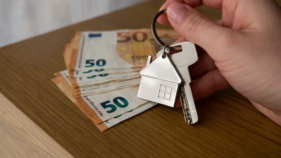 Een afbeelding van een hand die huissleutels vasthoudt voor een paar bankbiljetten van vijftig euro
