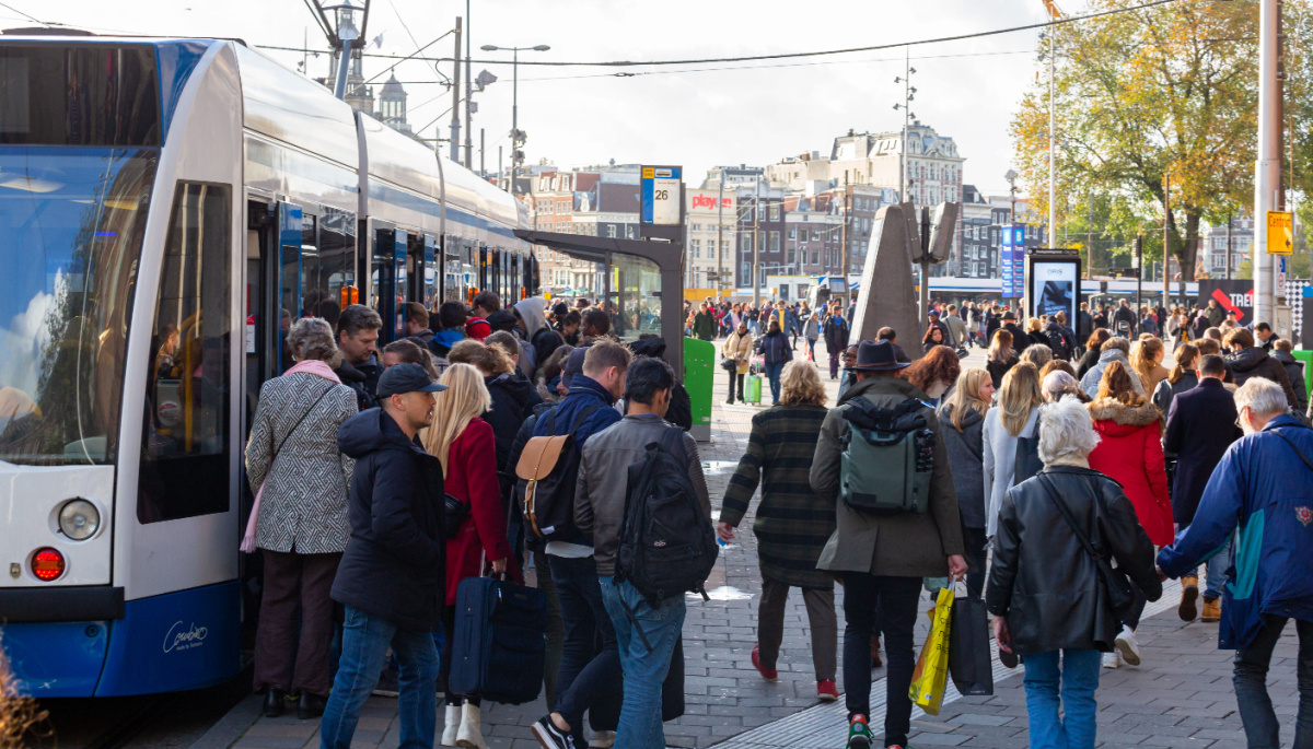 Een afbeelding van een groep mensen van alle leeftijdsgroepen bij een tram, Amsterdam, Nederland