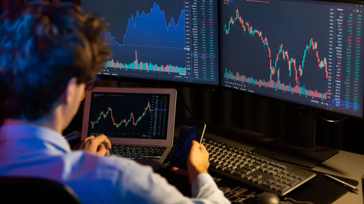 Man bekijkt koersgrafieken achter computer Man bekijkt koersgrafieken achter computer